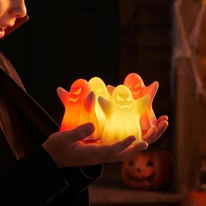Close-up shot of glowing ghost LED night lights held in hands for Halloween party decor.