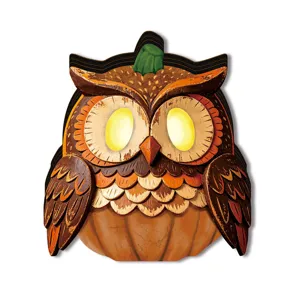 Close-up detail of Halloween luminous owl wooden ornament with retro glowing pumpkin eyes decor.