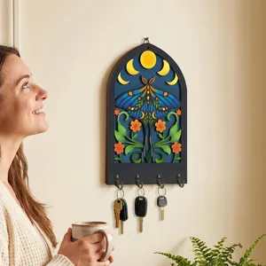 Close-up view of bohemian wooden key holder wall decor featuring moth and moon phase design.