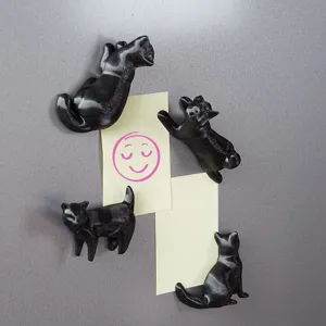 Detailed view of 3D printed black cat fridge magnets holding yellow notes on metal surface.