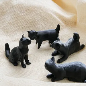 Close-up of cute black cat 3D printed fridge magnets, detailed texture and unique poses on fabric.