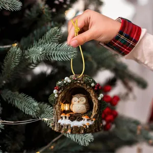 Detailed shot of a charming Christmas tree hanging ornament featuring an owl in a snowy hollow tree.
