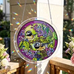 Stained acrylic suncatcher hanging ornament with birds and floral design, sunny window view.