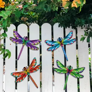Detailed shot of colorful metal dragonfly wall decor hanging on garden fence for outdoor art.