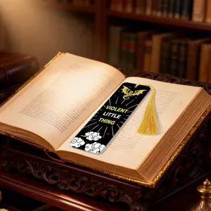 Close-up of a black acrylic bookmark with gold tassel, dragon motif, and English quote detail.