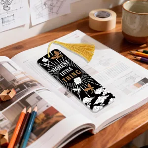 Detailed display view of acrylic bookmark with tassel and dragon pattern on rustic book desk.