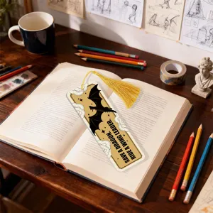 Close-up of creative dragon pattern bookmark with tassel on open book, cozy desk setup detail.