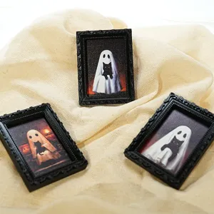 Gros plan de mini cadres magnétiques fantôme chat noir d'Halloween sur tissu texturé.