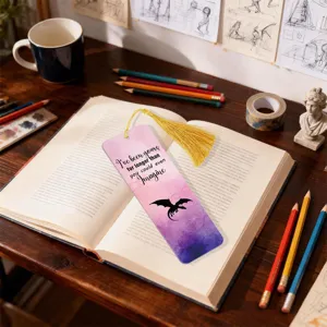 Detailed view of a colorful gradient dragon bookmark with a yellow tassel on an open book.