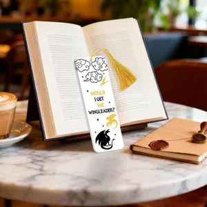 Close-up detail shot of a creative fantasy dragon bookmark with gold tassel on marble table.