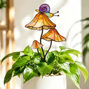 Gros plan sur le piquet de plante escargot et champignon en verre coloré et métal dans le pot vert.