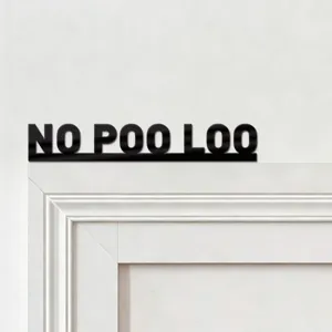 Close up detail of black acrylic door sign with text no poo loo against white wall.