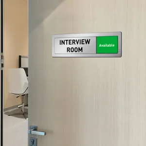 Close-up of brushed metal sliding door sign for office meeting room status display detail.