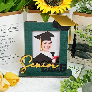 Dettaglio cornice foto laurea in legno con scritta dorata Senior 2026 e cappello nero.