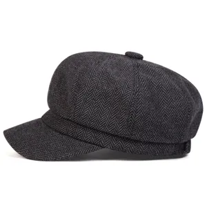 Vista laterale dettagliata di un berretto newsboy grigio scuro in tweed con motivo spina di pesce.