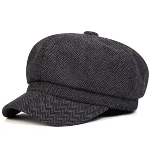 Vista dettagliata del berretto newsboy in tweed grigio scuro a spina di pesce con visiera.