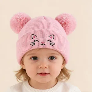 Détail de bonnet tricoté rose avec visage de chat brodé mignon et pompons doubles duveteux.