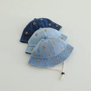 Detail view of cute children denim bucket hats with bear embroidery and adjustable chin strap.