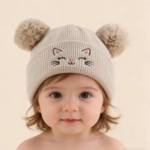 Gros plan détaillé du joli bonnet tricoté avec une broderie de chat et de beaux pompons.