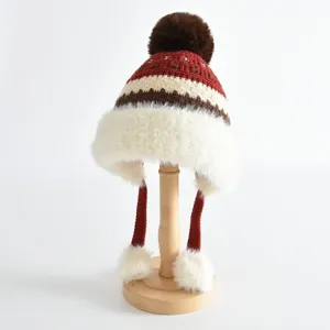 Vue detaillee de la garniture en peluche duveteuse et de la texture tricotee du bonnet enfant.