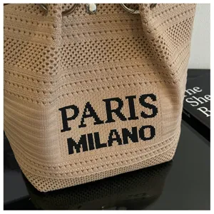 Primo piano dettagliato di una elegante borsa a secchiello in maglia kaki con testo nero.