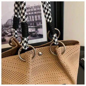 Dettaglio ravvicinato della borsa in maglia con manico pied-de-poule e anello in metallo.