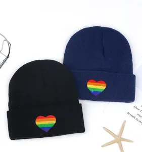 Vista detallada de gorros de punto de invierno con bordado de corazón arcoíris, cálidos y chic.