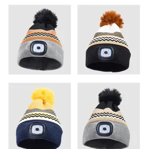 Unisex winter warm knitted beanie hat with built-in LED headlamp and fluffy pom-pom.