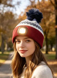 Close-up of knitted LED beanie with front rechargeable light and fluffy pom-pom detail.