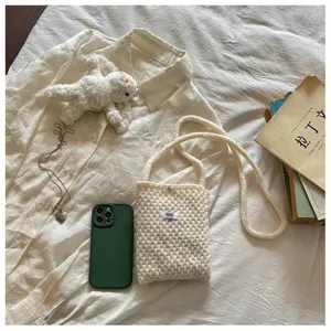 Vue détaillée du sac bandoulière et de la pochette téléphone en tricot écru, style à plat.