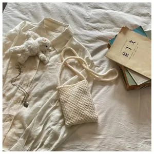 Vue détaillée d'un sac bandoulière tricoté crème, accessoire quotidien décontracté et chic.