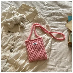 Détail de sac bandoulière tricoté rose montrant une texture douce et une jolie mini taille.