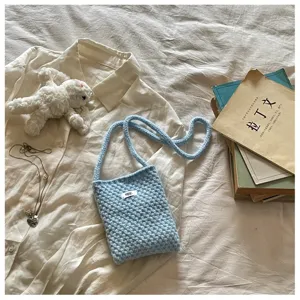 Détail de mini sac bandoulière tricoté bleu, pochette téléphone et monnaie esthétique.