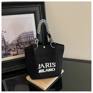 Vista dettagliata della borsa a mano in maglia nera con manico pied-de-poule e testo.