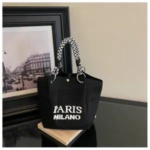 Scatto dettagliato di un'elegante borsa a secchiello in maglia nera con manici pied-de-poule.