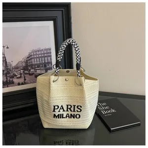 Primo piano della borsa a secchiello in maglia bianca con lettere nere e dettagli chic.