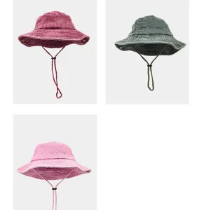 Dettaglio in primo piano del cappello da pescatore in cotone con cordino e tesa larga.