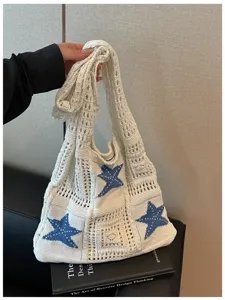 Gros plan sur les superbes détails du sac bandoulière en tricot blanc motif étoile.