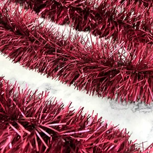 Close-up detail of dark red metallic tinsel garland, festive decoration ribbon for parties.