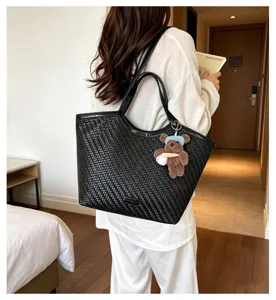 Fashionable large capacity woven tote bag with cute bear keychain for women commuter daily.