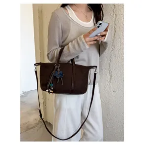 Detailed view of women's brown suede commuter dumpling crossbody bag with cute charm.