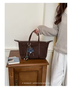 Stylish brown suede tote bag with flower charm, perfect for daily commuting and retro outfits.