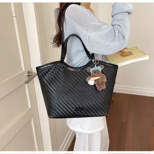 Detail view of the black woven leather large capacity tote bag featuring cute bear charm.