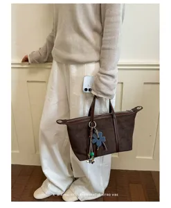 Brown suede dumpling tote bag for women, retro commuter shoulder bag with chic charm detail.