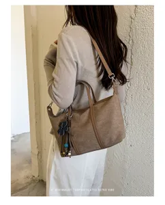 Detailed view of women retro suede shoulder dumpling bag with cute charms, minimalist style.