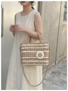 Woven straw handbag detail showing daisy flower decoration and crossbody strap texture.