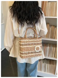 Detail view of a stylish straw woven shoulder bag with a cute daisy flower and top handle.