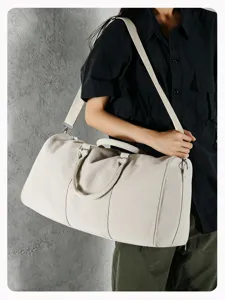 Close-up of a stylish beige canvas duffel bag, showing durable material and sturdy handle details.