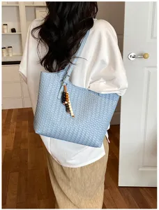 Primer plano detallado del bolso tote tejido con un elegante colgante de cuentas.