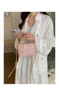 Close-up detail of the pink quilted crossbody bag with gold chain strap and chic floral lock.